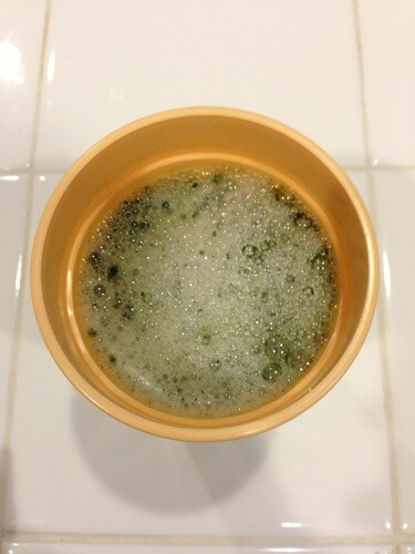 Water in cup with green powder Water in cup with green powder
