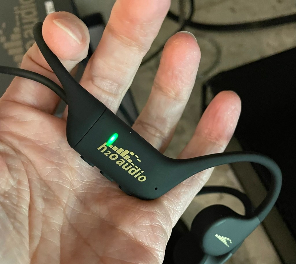 H2Oaudio Tri2 Headphones charged with a green light