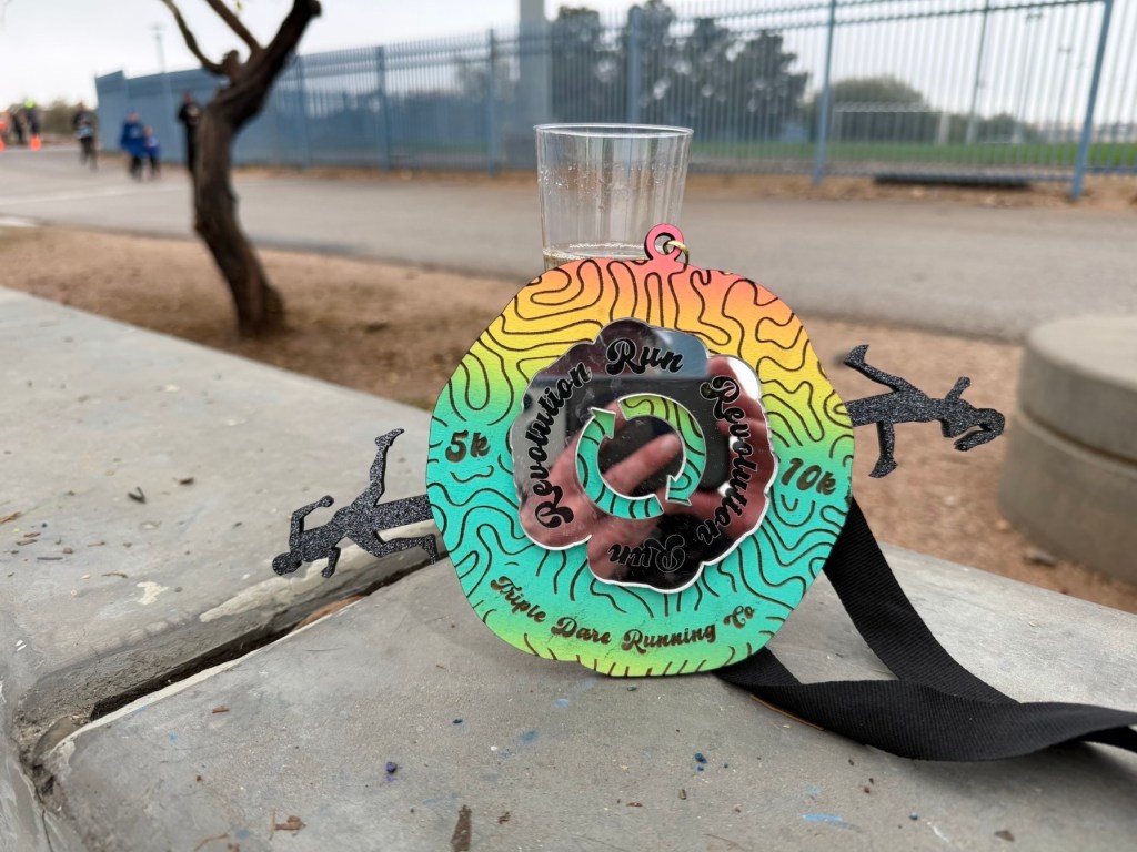 Medal and glass of fake champagne from 2026 Revolution run 5k